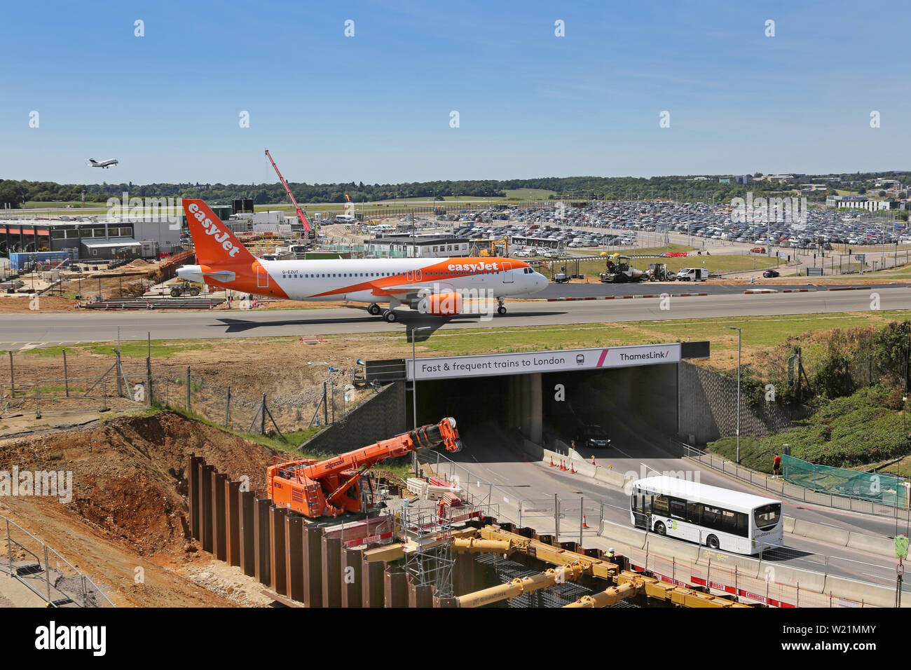 London Luton Airport, UK. Main access road running beneath airport taxiway with Easyjet plane passing. Excavation for new DART rail link in foreground Stock Photo