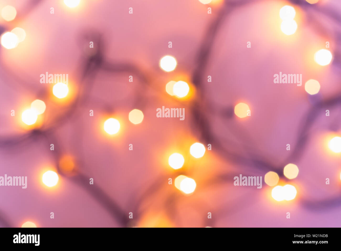 Christmas or party concept. Golden bokeh lights on blurred pink background. Stock Photo