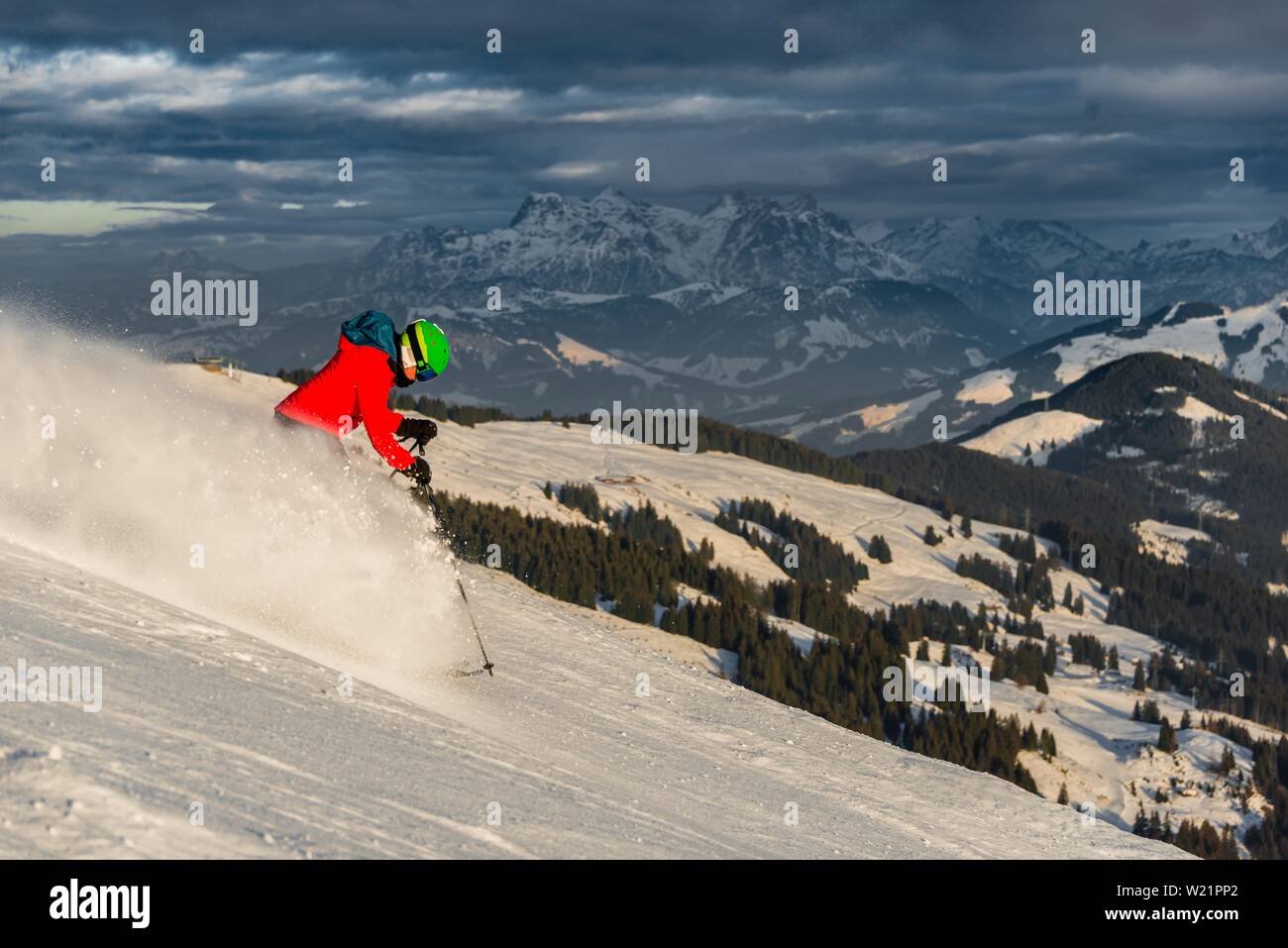 Female skier skiing steep downhill, black piste, behind mountains, Brixen im Thale, Tyrol, Austria Stock Photo