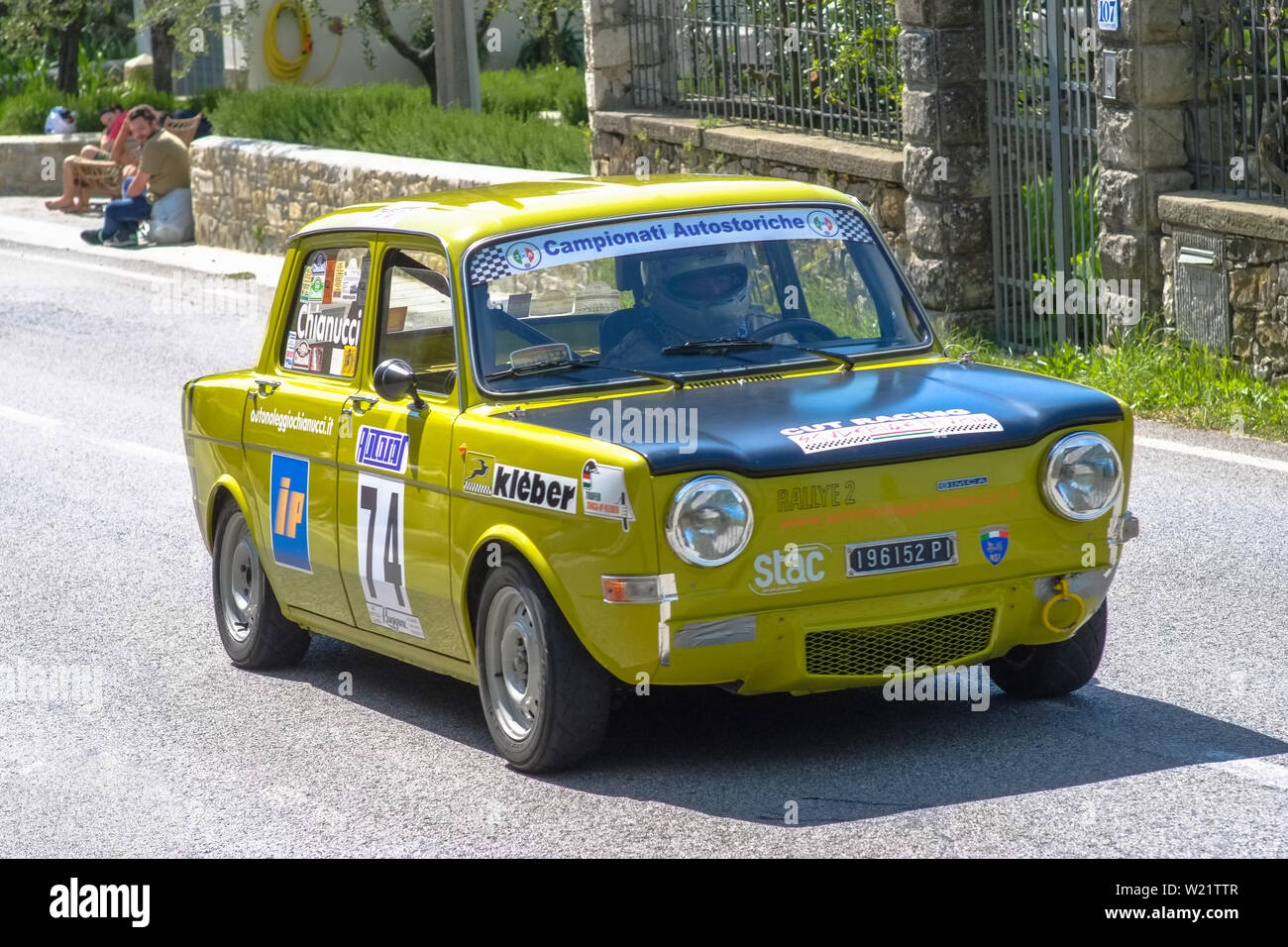 19th century old Fiat 128 car competes for the main race with a countryside landscape around the track. Stock Photo