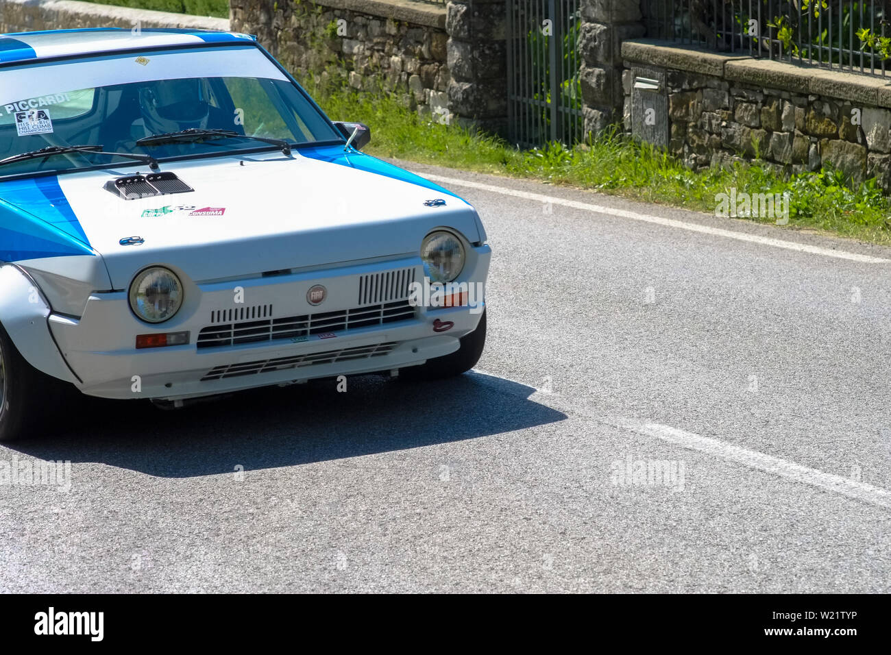 19th century old Fiat Ritmo car competes for the main race with a countryside landscape around the track. Stock Photo