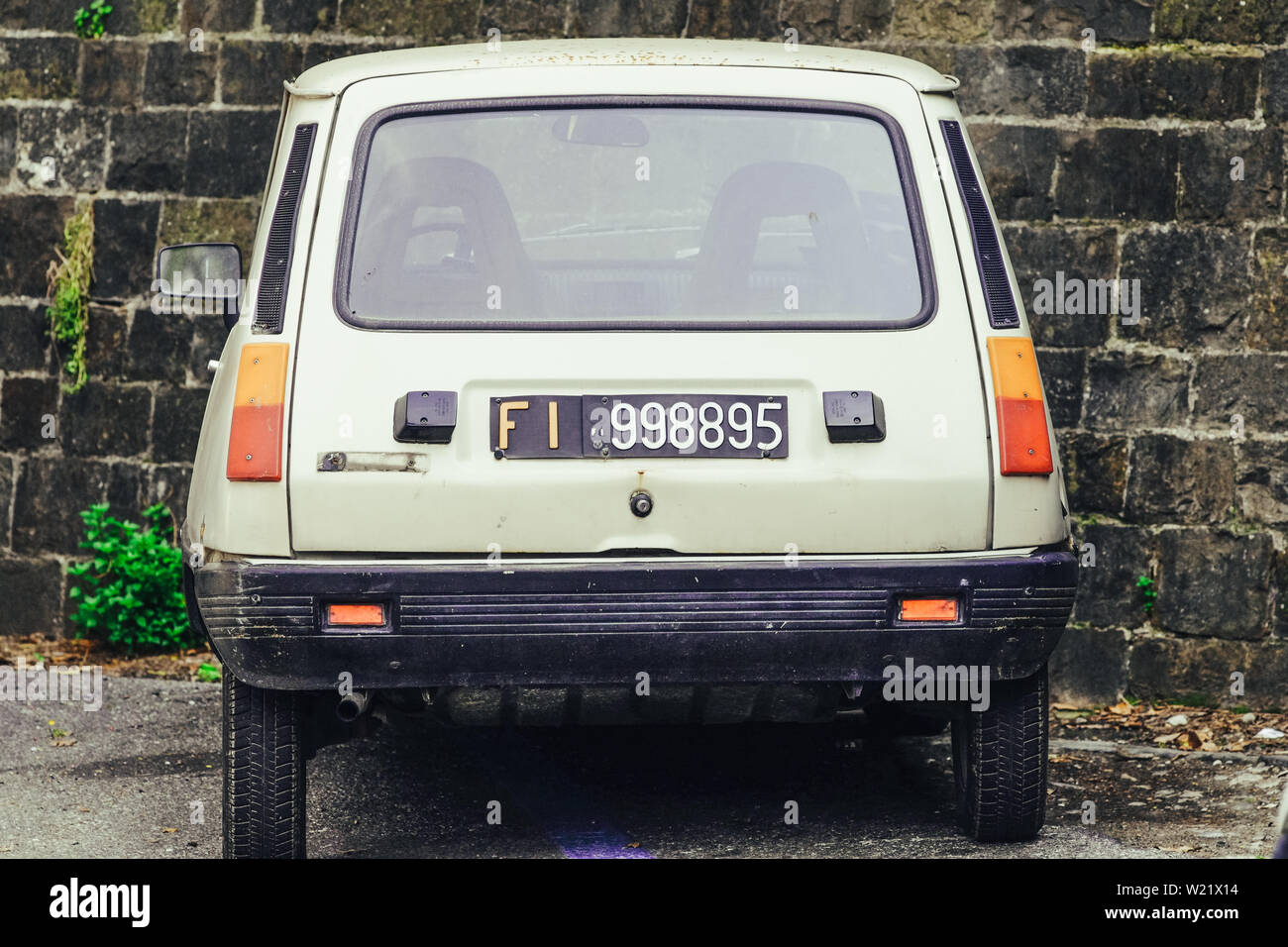 Old retro car  Ranault 5 parked beside an ancient wall. Florence Tuscany, Italy Stock Photo
