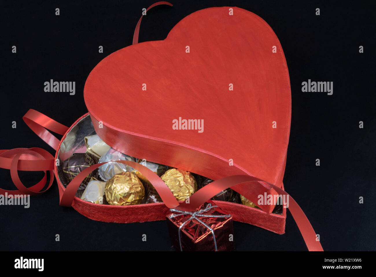 Declaration of love: to offer a box of chocolates in the shape of heart, of passion red color Stock Photo