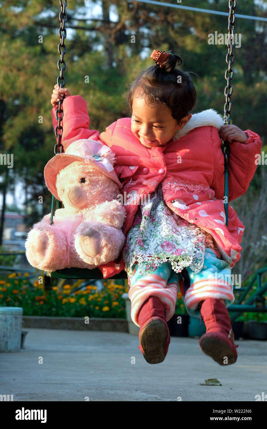 Girl (3 1/2 years old) swings with her giant teddy at the 'Ferrando Transit Shelter Home' children's home of the Sisters of the Order of the Missionary Sisters of Mary Help of Christians (MSMHC) in Shillong, Meghalaya State, Northeast India Stock Photo