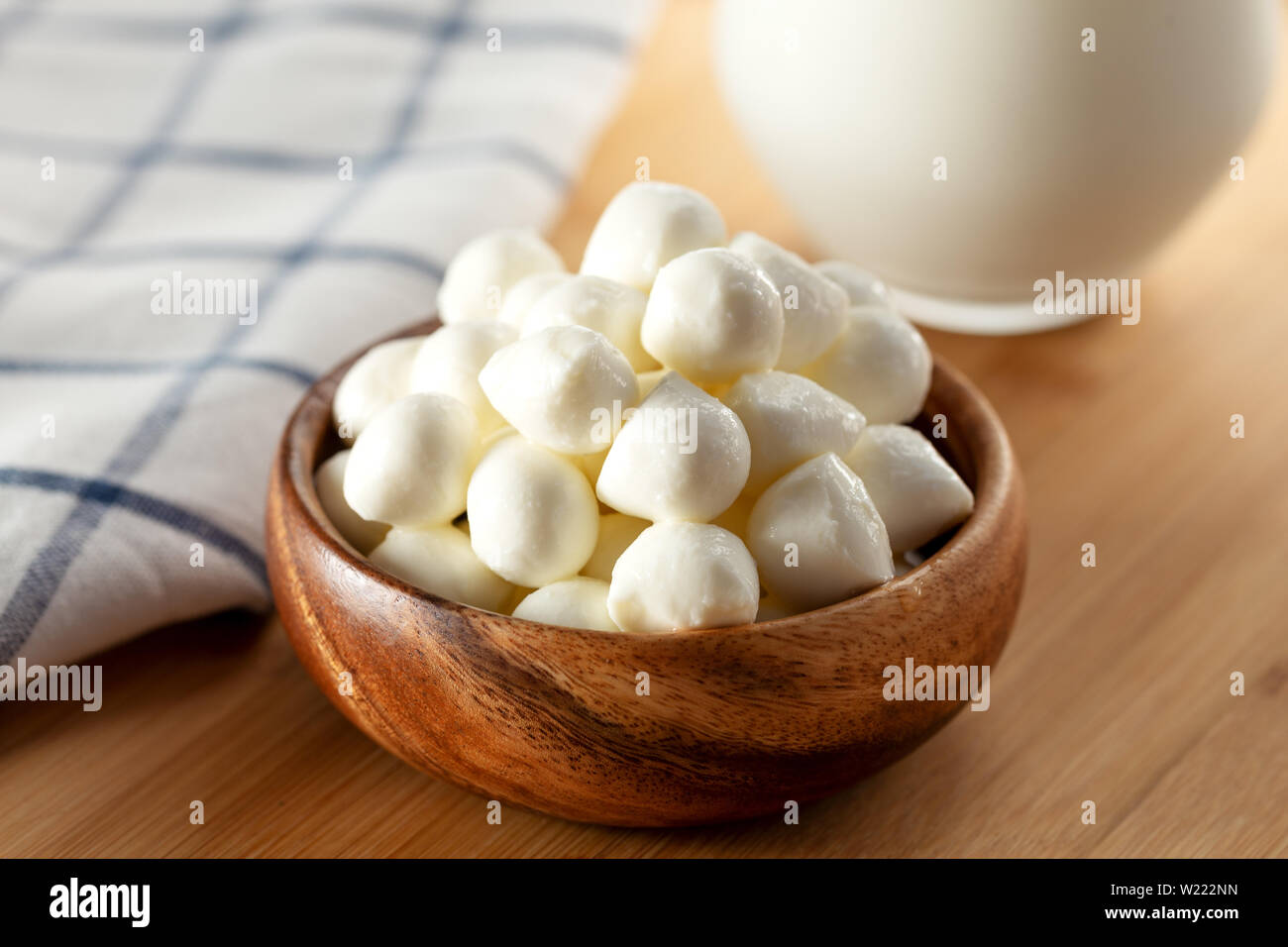 Mozzarella cheese balls in bowl and glass of milk on wooden background Stock Photo