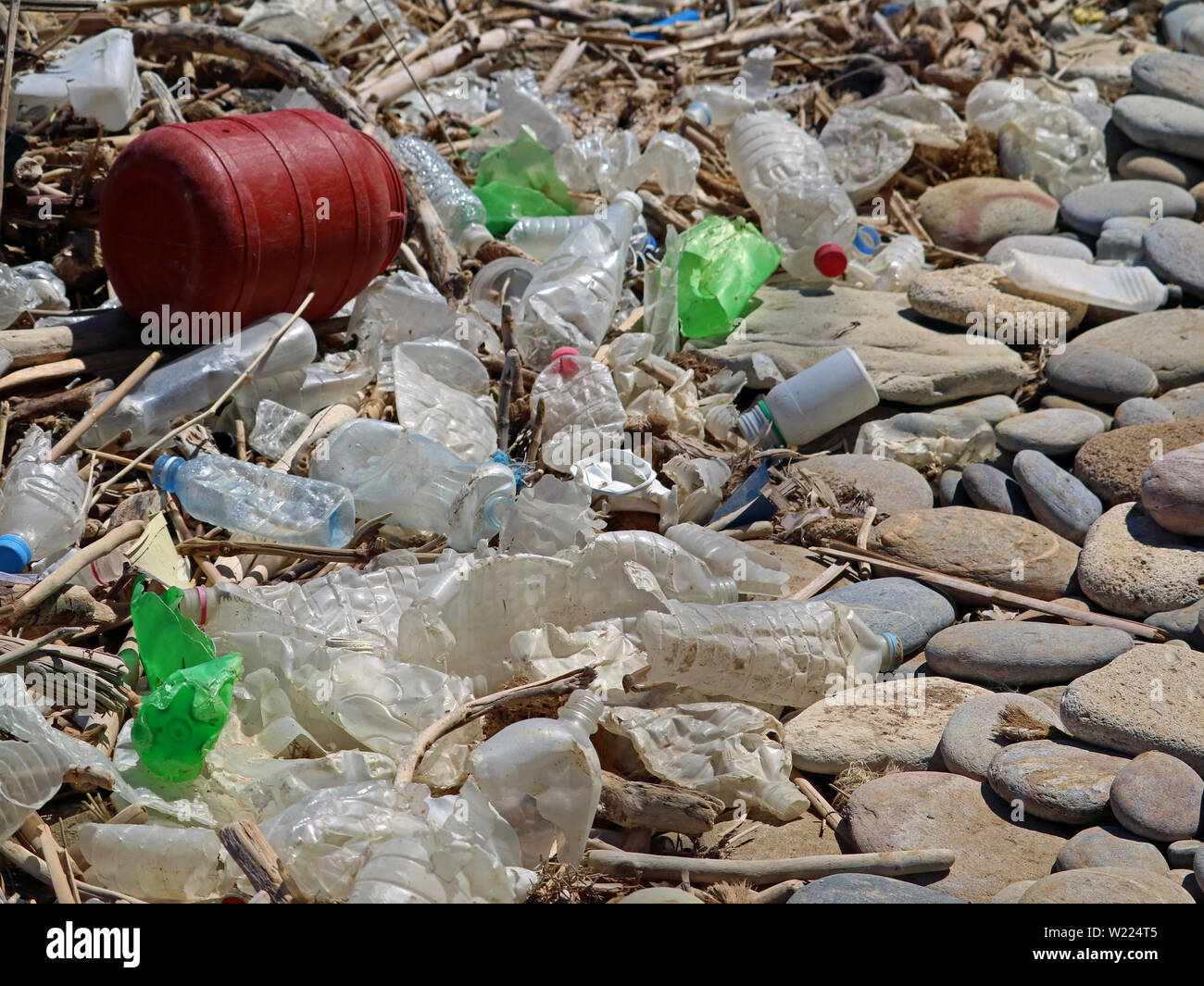 dirty plastic bottles and waste on the stone beach. Environmental pollution Stock Photo