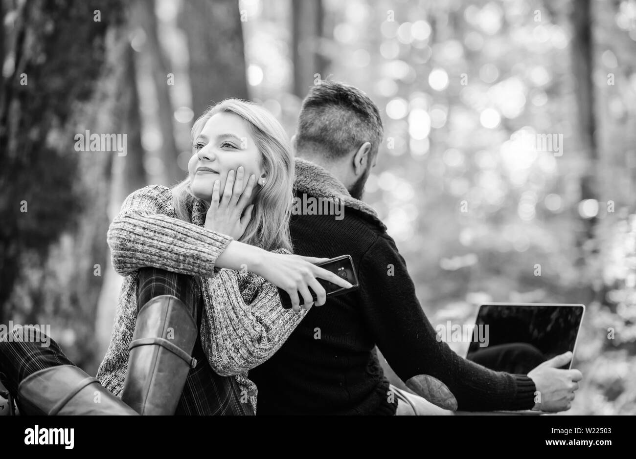 couple in love relax in autumn forest with phone and laptop. happy girl  dreaming outdoor. man sit with back. Spring mood. camping and hiking.  Family picnic. Relationship. Full concentration at work Stock, image size:1300x939