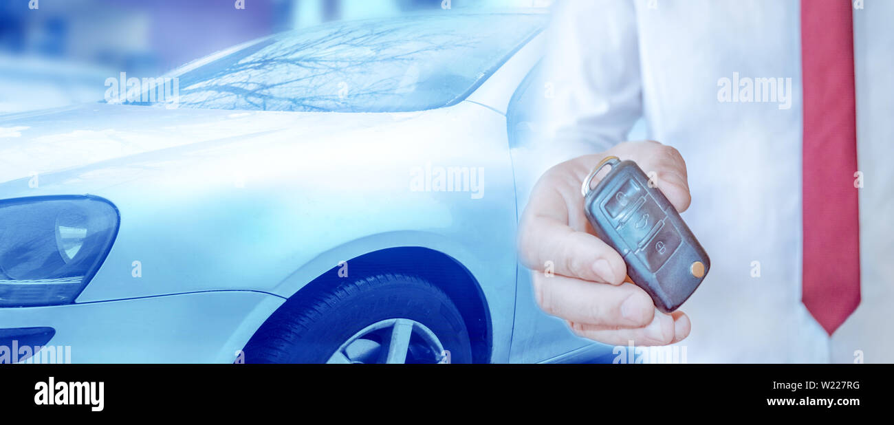 Car dealer holding a key. Auto dealership and rental concept background