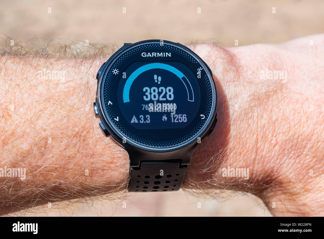 Garmin Smart Watch on male wrist displaying a step counter, distance traveled in kilometers and amount of calories burned Stock Photo