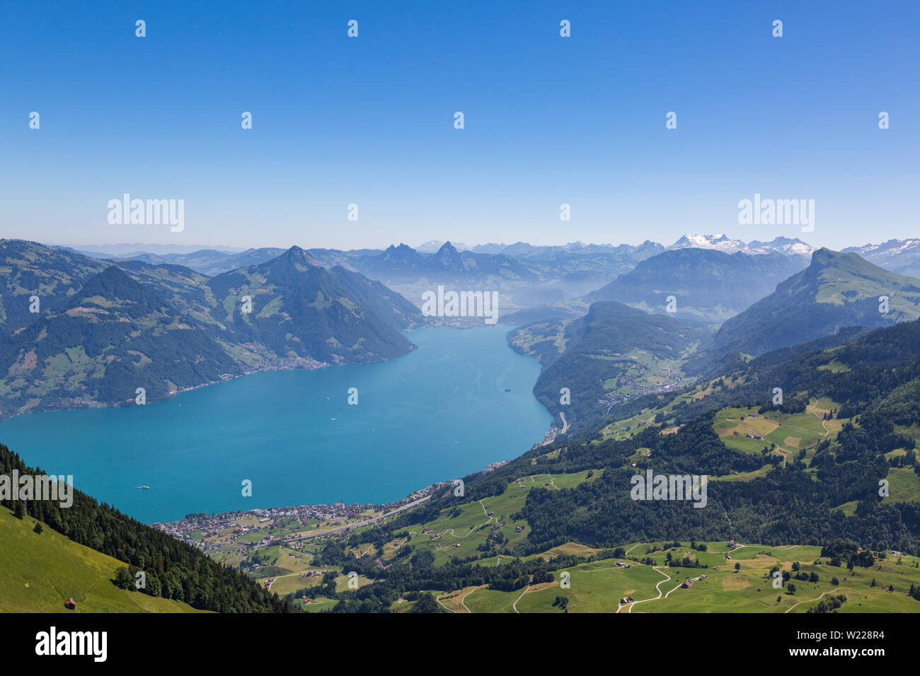 lake Lucerne with blue sky, Swiss alpine mountains, and village of Beckenried Stock Photo