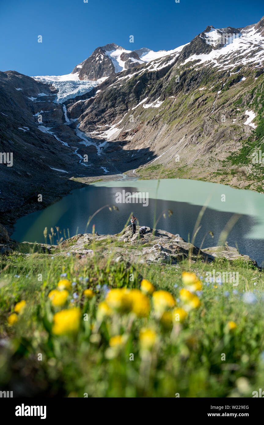 Wanderer am Triftsee mit Triftgletscher und mäanderndem Fluss in den Schweizer Alpen bei Gadmen Stock Photo