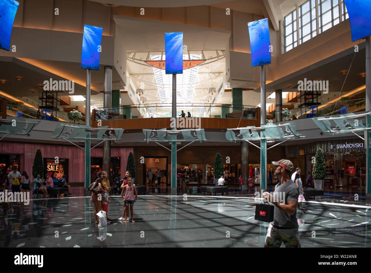 Orlando, Florida. June 6, 2019 .People enjoying their shopping trip in the main hall with top view of screens promoting big brands in The Mall at Mill Stock Photo