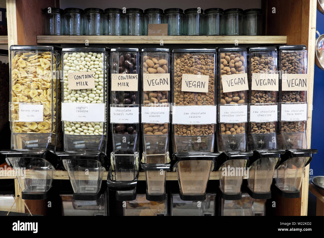 Food containers dispensers for selling loose Vegan nuts, grains, pulses on shelf inside zero waste refill shop interior Cardiff Wales UK  KATHY DEWITT Stock Photo