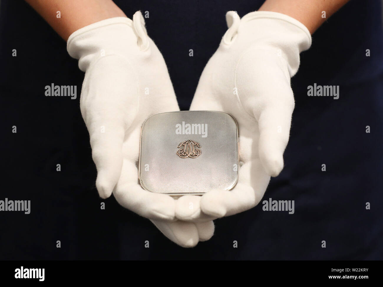 A Sotheby's employee handles a silver cigarette case, once belonging to Sir Winston Churchill, which will be included in Sotheby's upcoming English literature, history, children's books, and illustrations auction. Stock Photo
