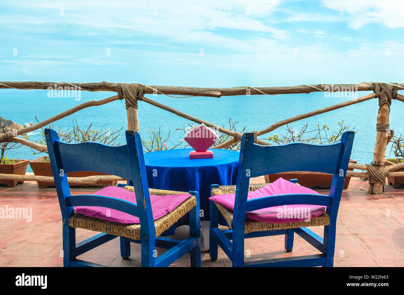 Coffee table on rustic balcony, with cliff and blue sea in background in Acapulco, Mexico. Stock Photo