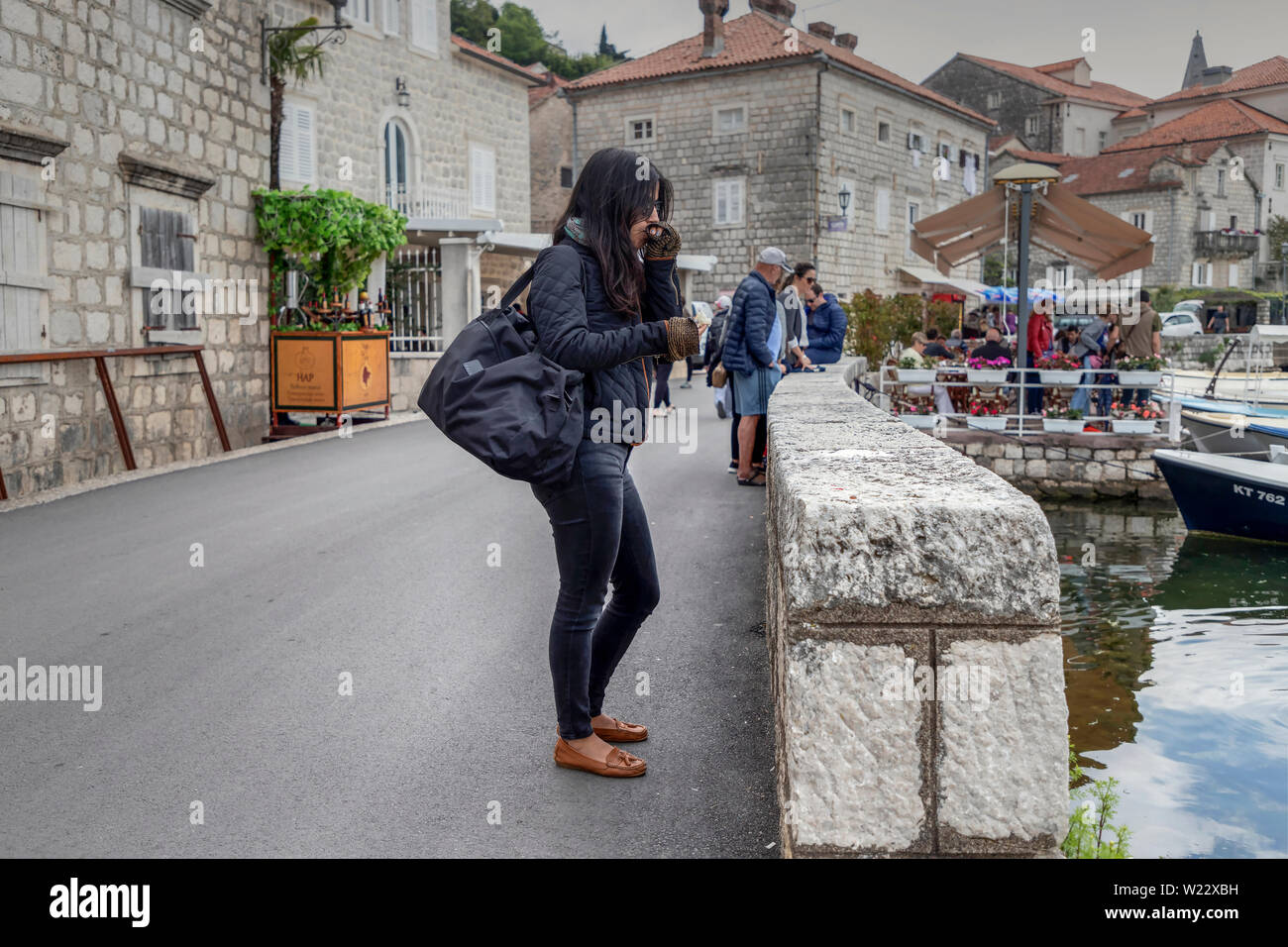 Montenegro, May 3rd 2019: Woman standing on the seaside road in Perast and observing the Bay of Kotor Stock Photo