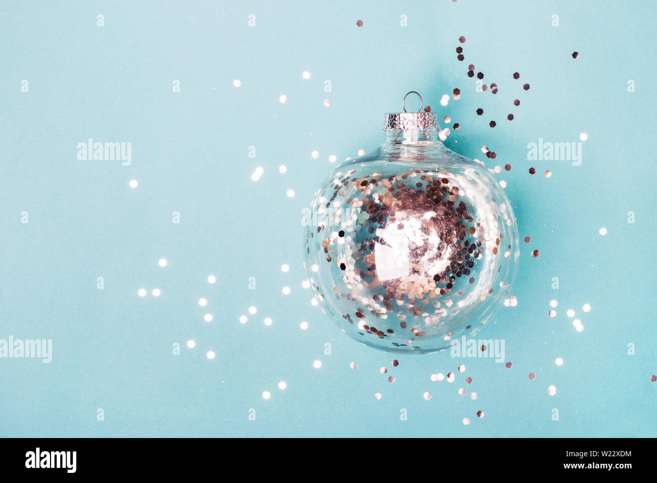 Christmas transparent ball with silver confetti on blue background