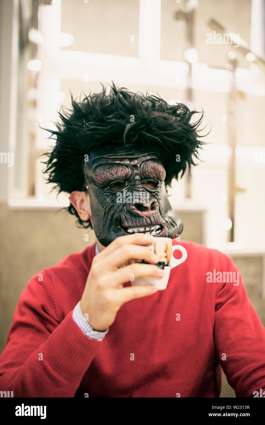 Man with gorilla mask drinking coffee in bar Stock Photo Alamy