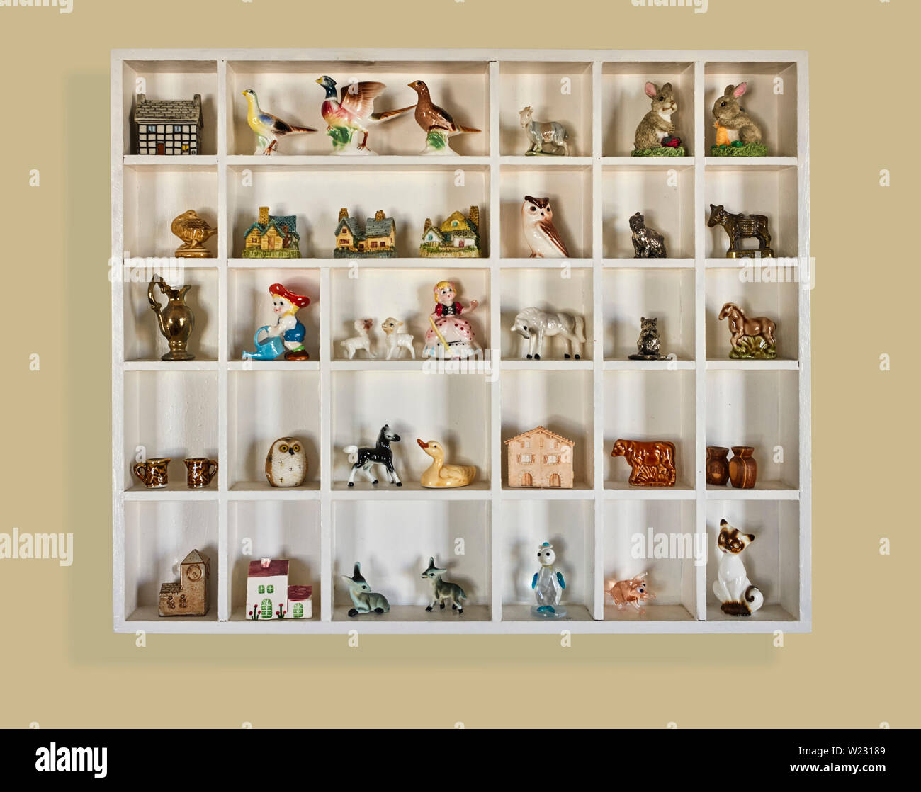 A box of small china figures and animals in a wall display unit Stock Photo