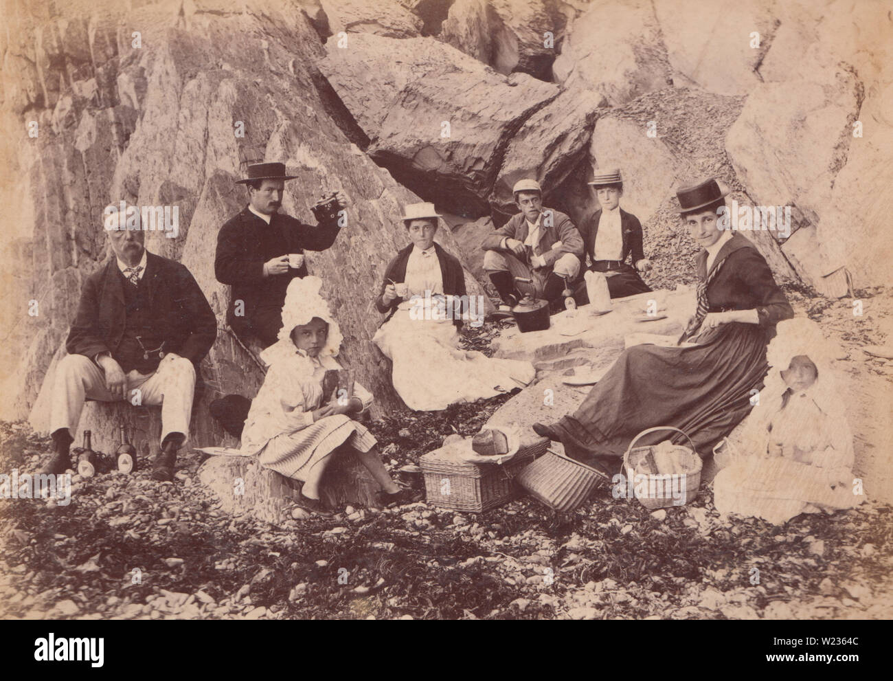 Victorian 1889 Photograph of a Family Sat on The Rocks on Borth Beach, Wales. This Fashionable Family are Having a Picnic. Stock Photo