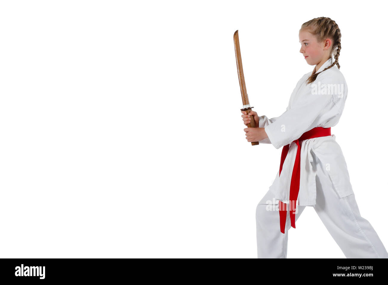Preteen caucasian girl wearing a karate uniform performing a sword