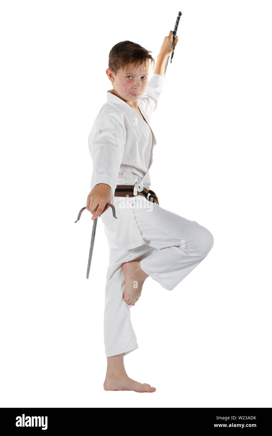 Teenage caucasian boy wearing a karate uniform performing kata with Sai