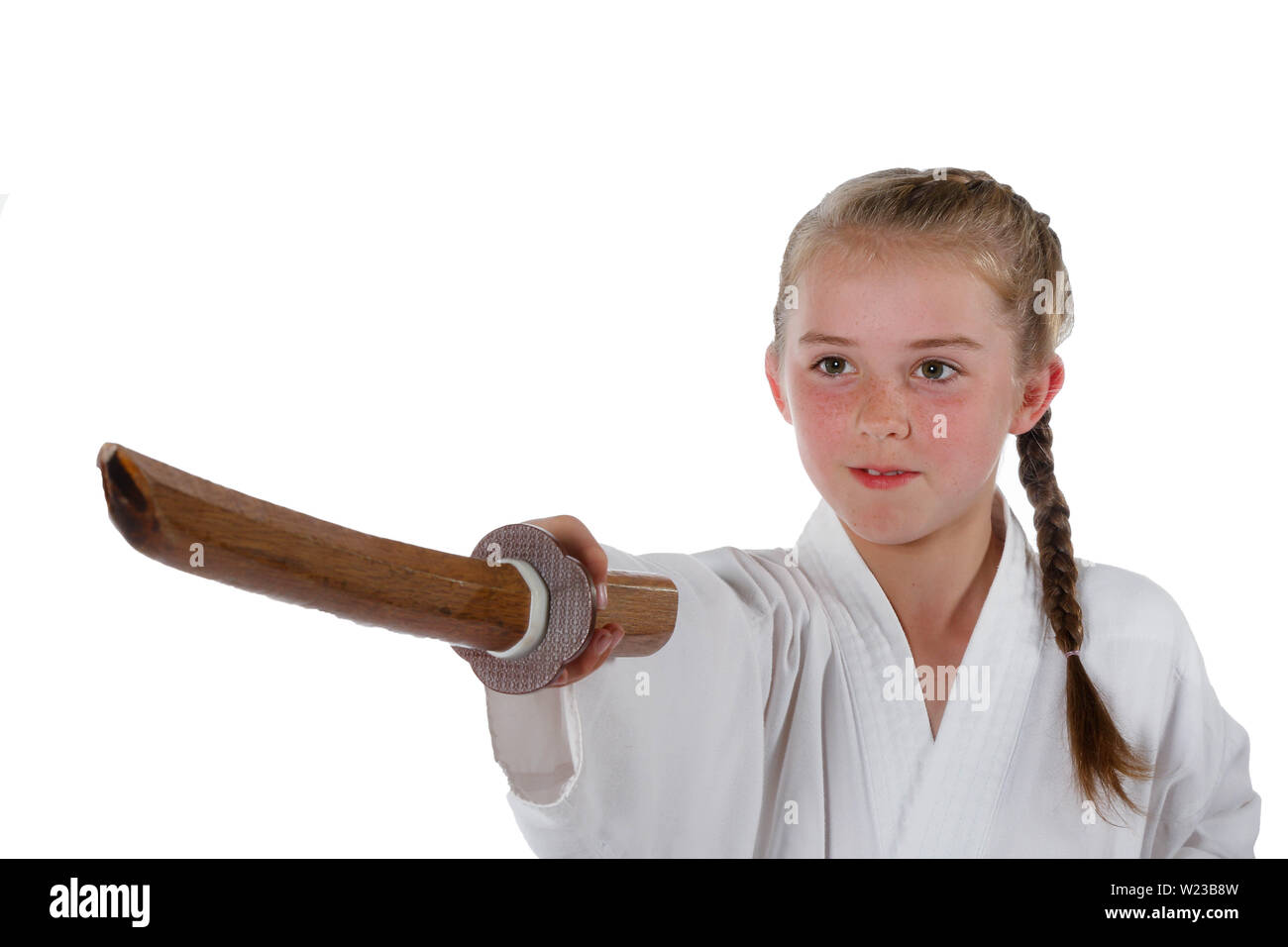Preteen caucasian girl wearing a karate uniform performing a sword