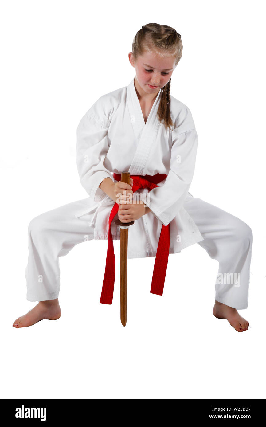 Preteen caucasian girl wearing a karate uniform performing a sword