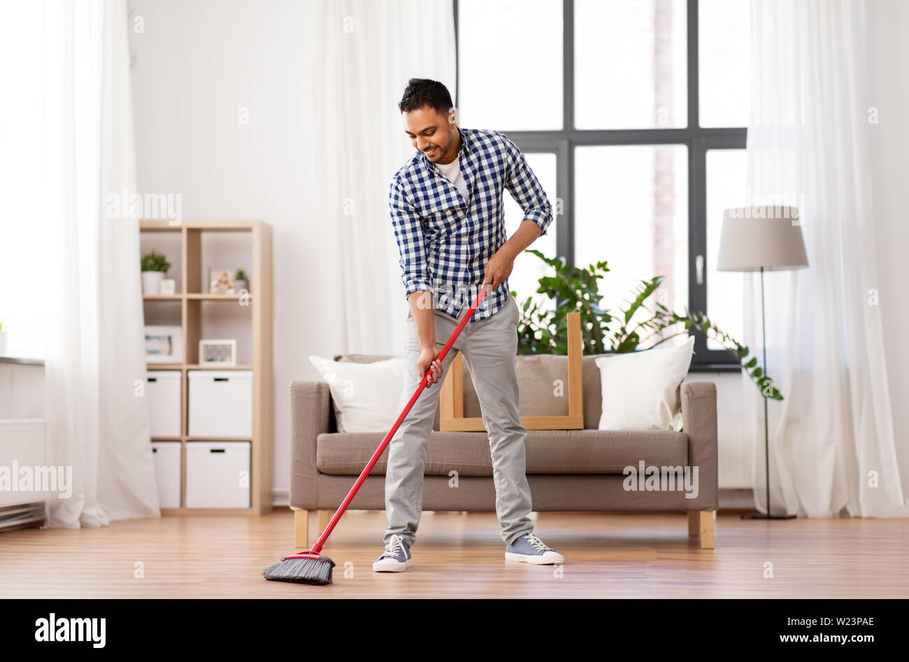 man with broom cleaning floor at home Stock Photo