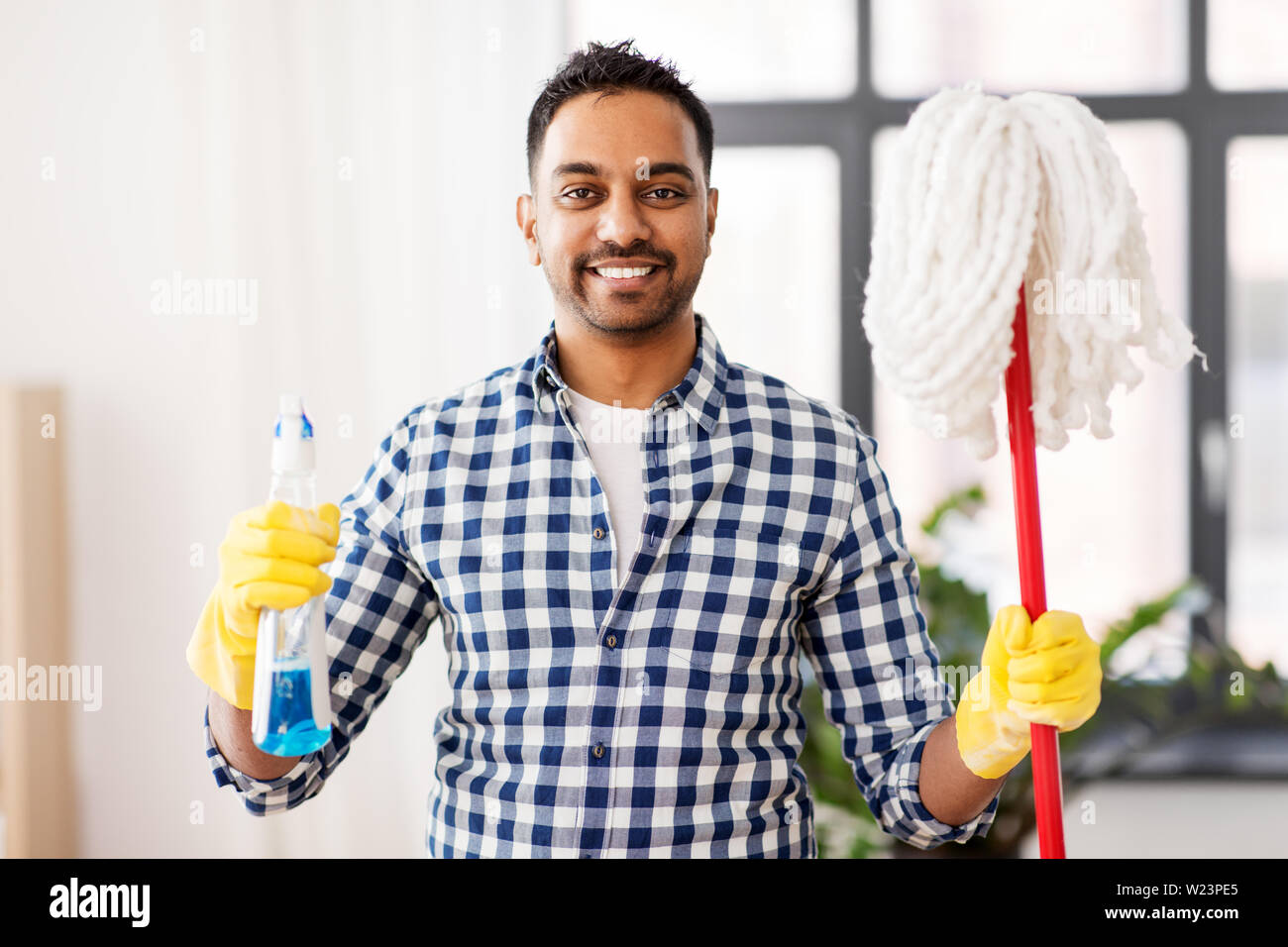 indian man with mop and detergent cleaning at home Stock Photo