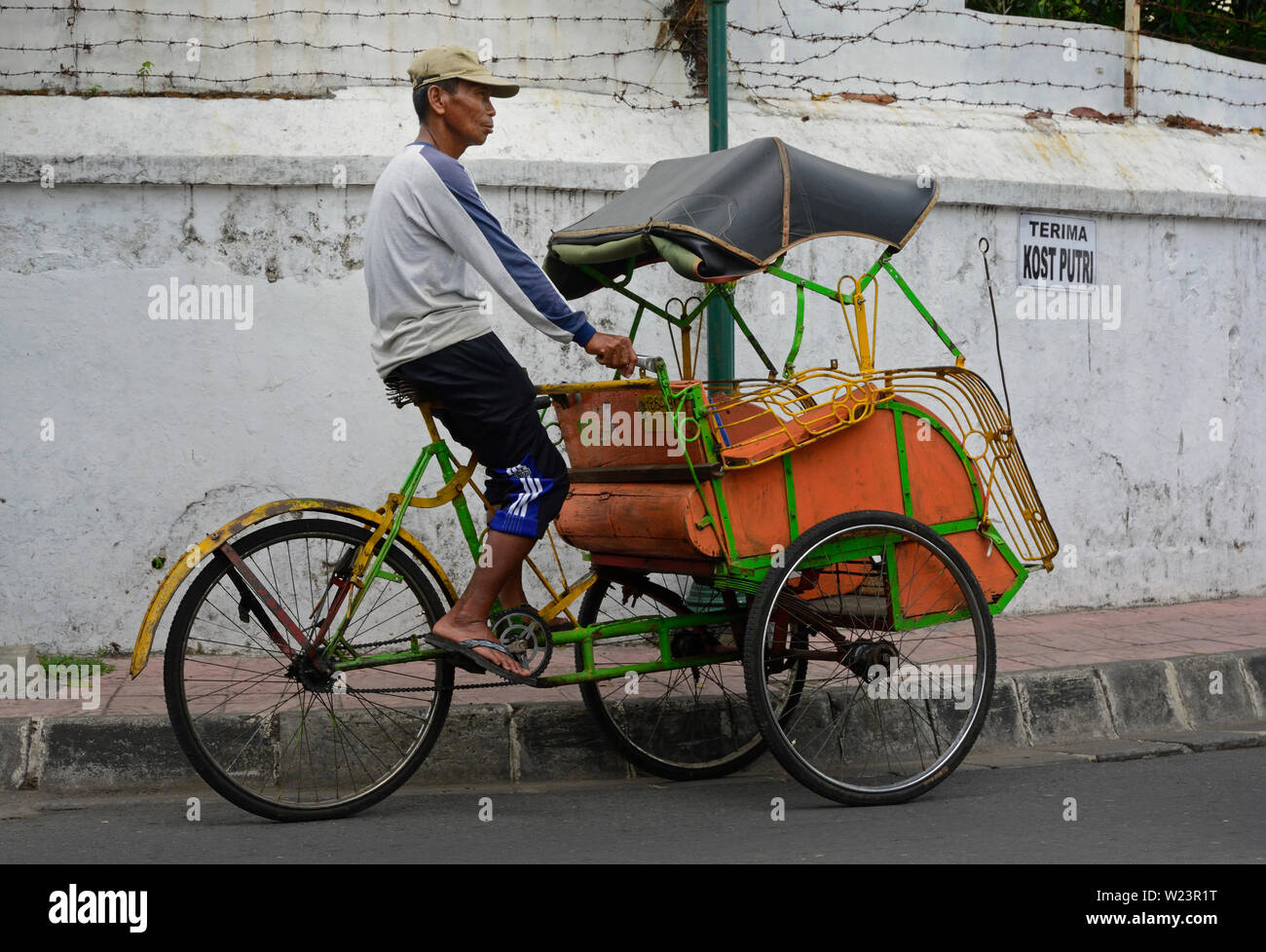 yogyakarta, di yogyakarta/indonesia - november 10, 2015: a becak driver on his vehicle on a road in yogyakarta looking out for clients Stock Photo
