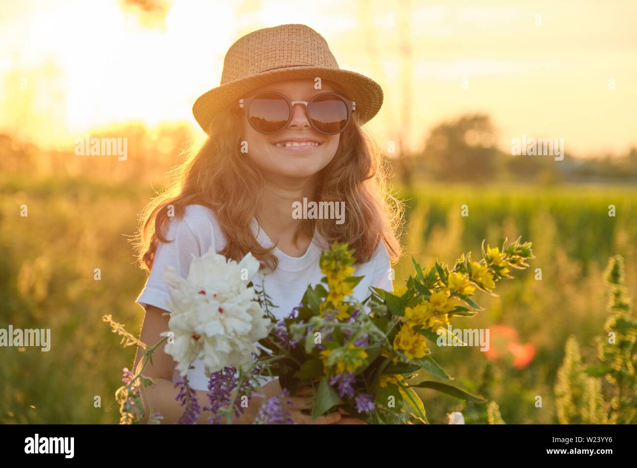 Outdoor portrait of a little girl with flowers on a sunny meadow ...