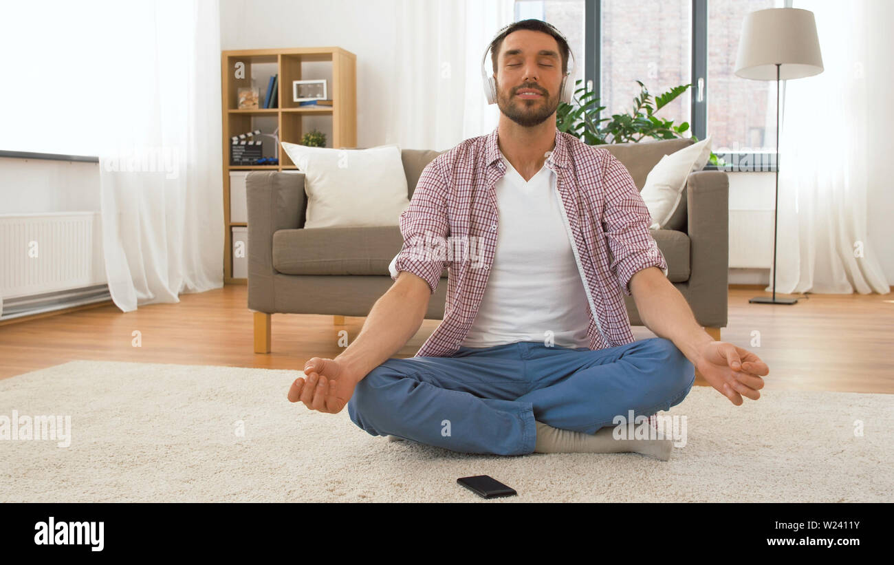 man in headphones meditating in lotus pose at home Stock Photo - Alamy