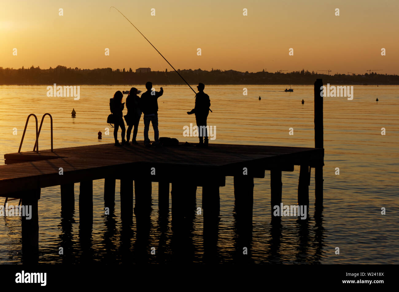 Group of young people fishing and talking on pier, unrecognizable persons Stock Photo