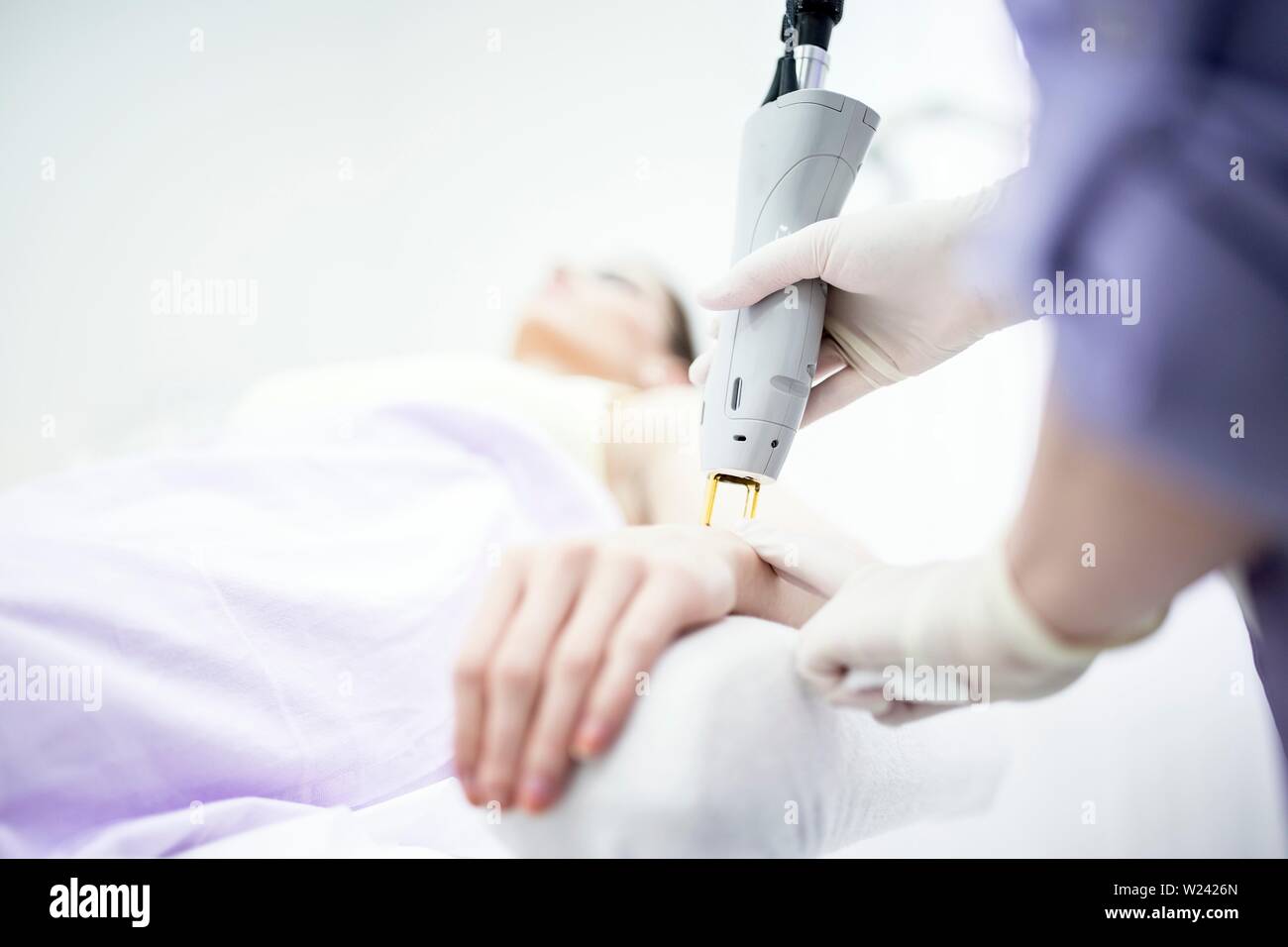 Young woman getting laser hair removal treatment on wrist, close-up. Stock Photo