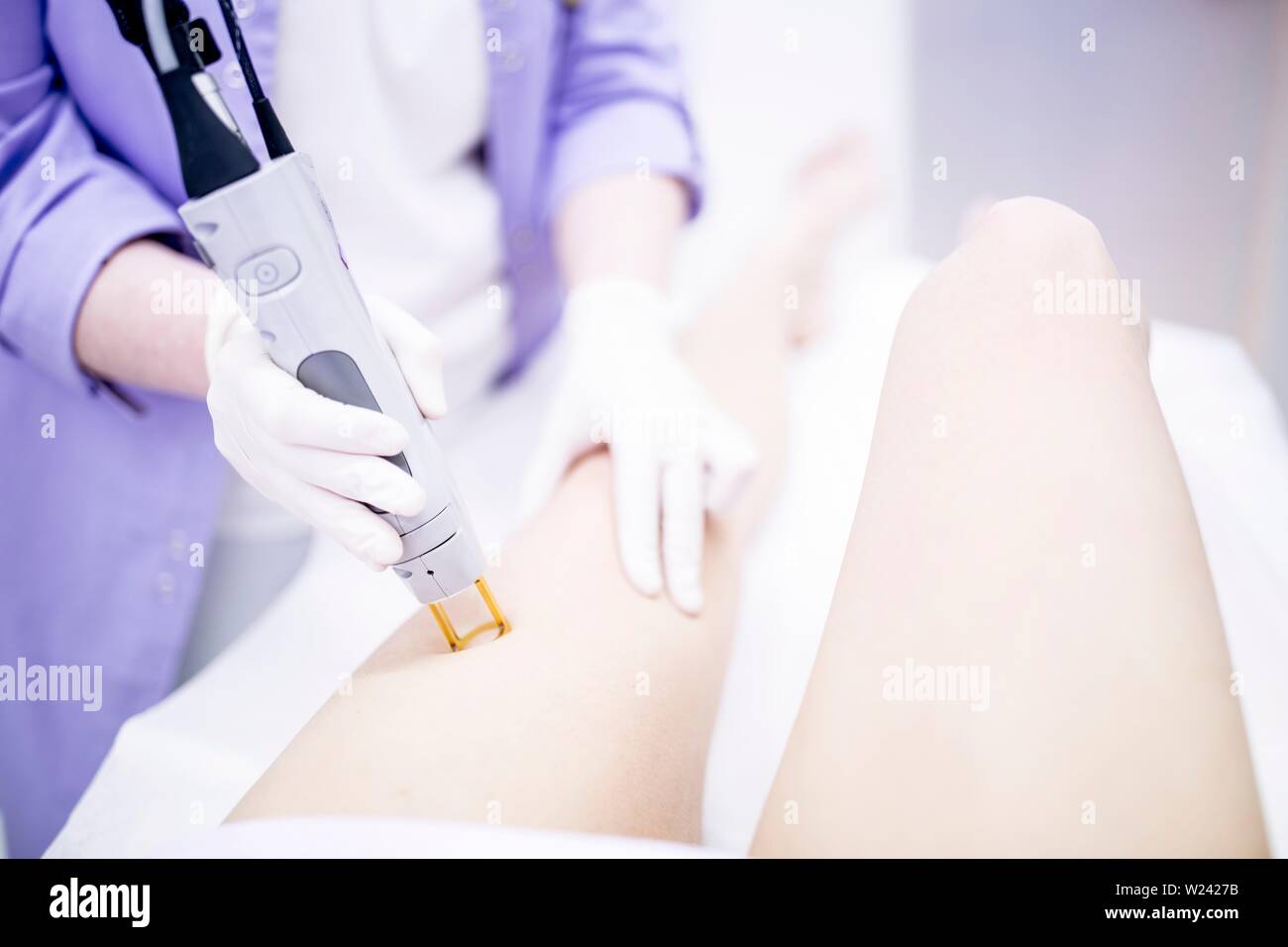 Young woman getting laser hair removal treatment on leg, close-up. Stock Photo