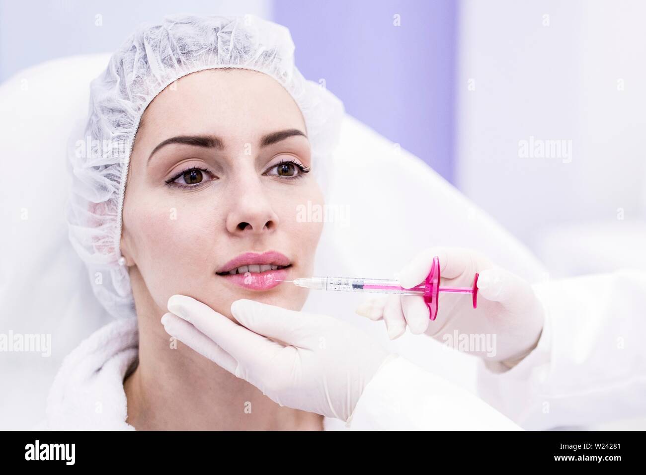 Dermatologist injecting botox injection on woman's lips, close-up. Stock Photo