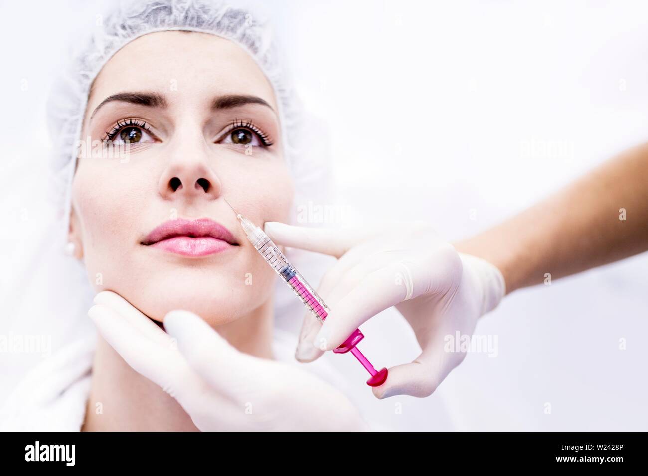 Young woman injecting botox injection on face, close-up. Stock Photo