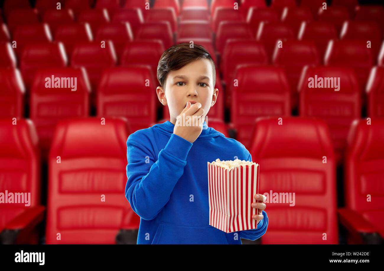 boy in blue hoodie eating popcorn at movie theater Stock Photo Alamy