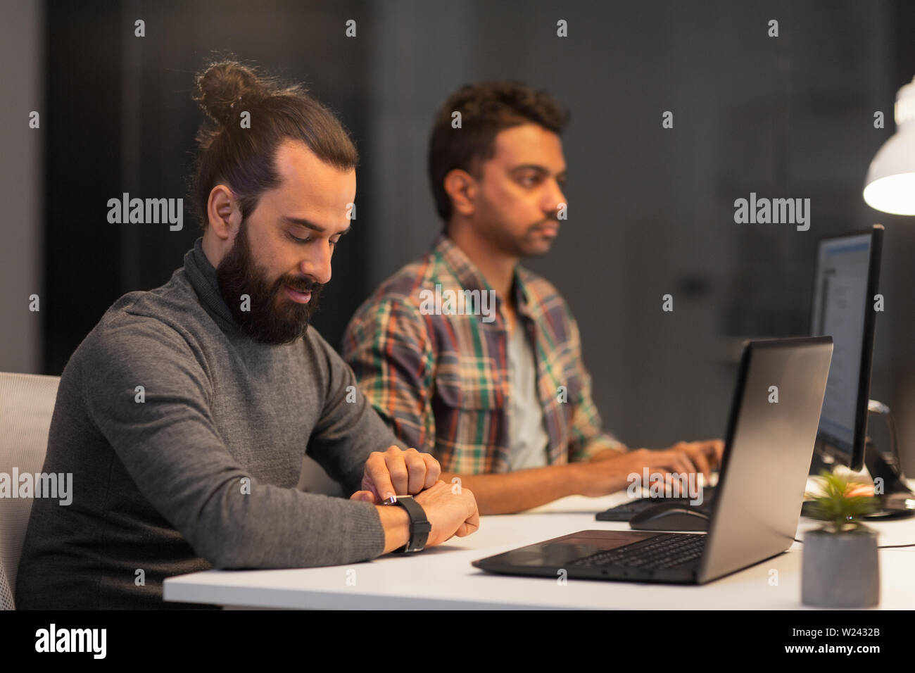 creative man with smartwatch works at night office Stock Photo