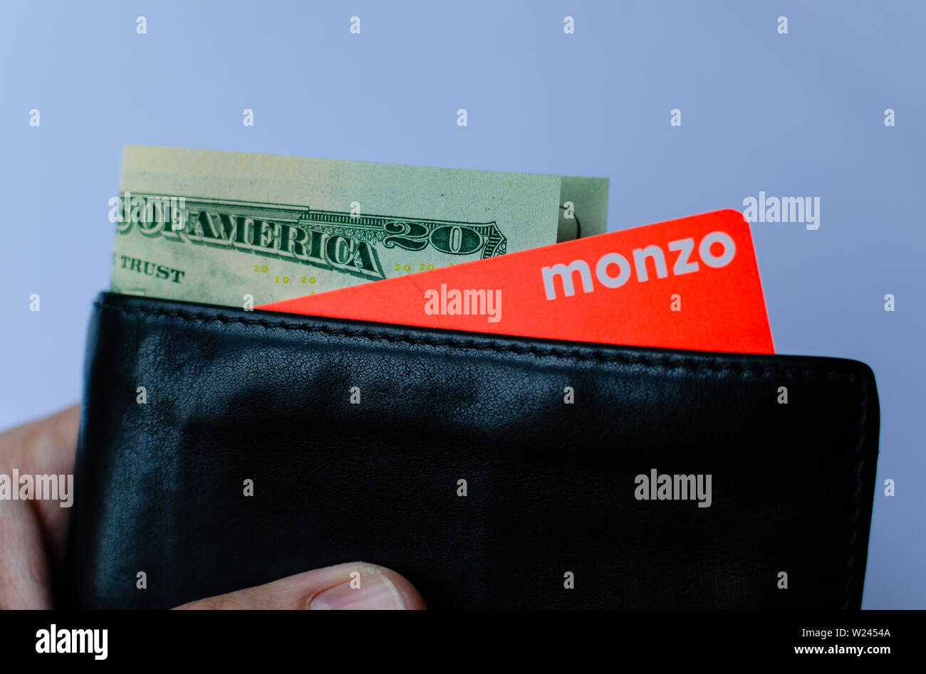 Monzo bank card with 20 dollar bill sticking out from the wallet. Stock Photo