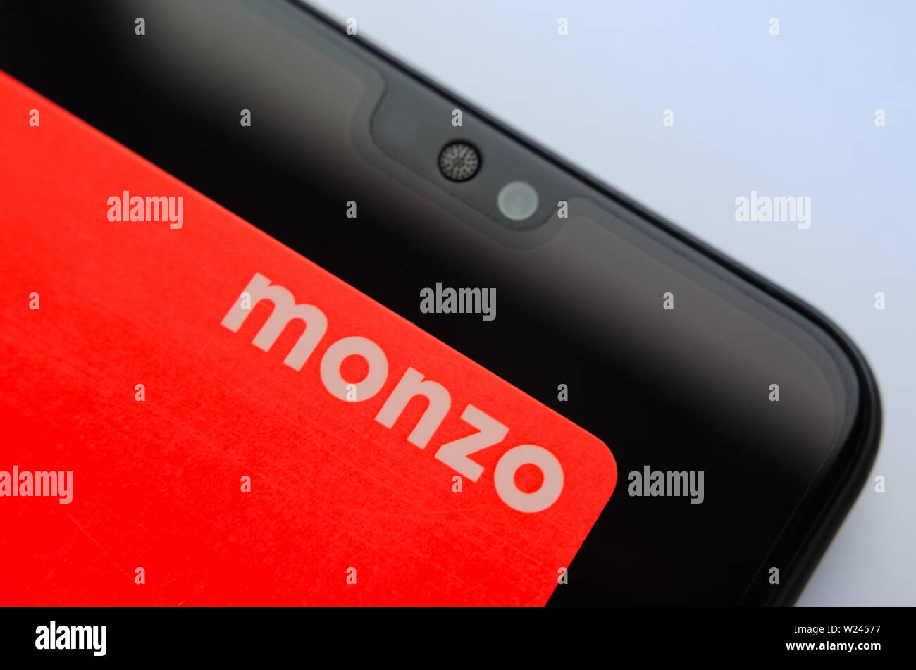 Monzo bank card on top of smartphone. Macro photo. Stock Photo