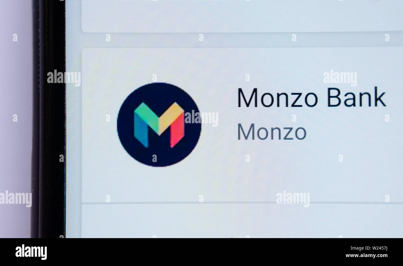 Monzo bank card on top of smartphone. Macro photo. Stock Photo