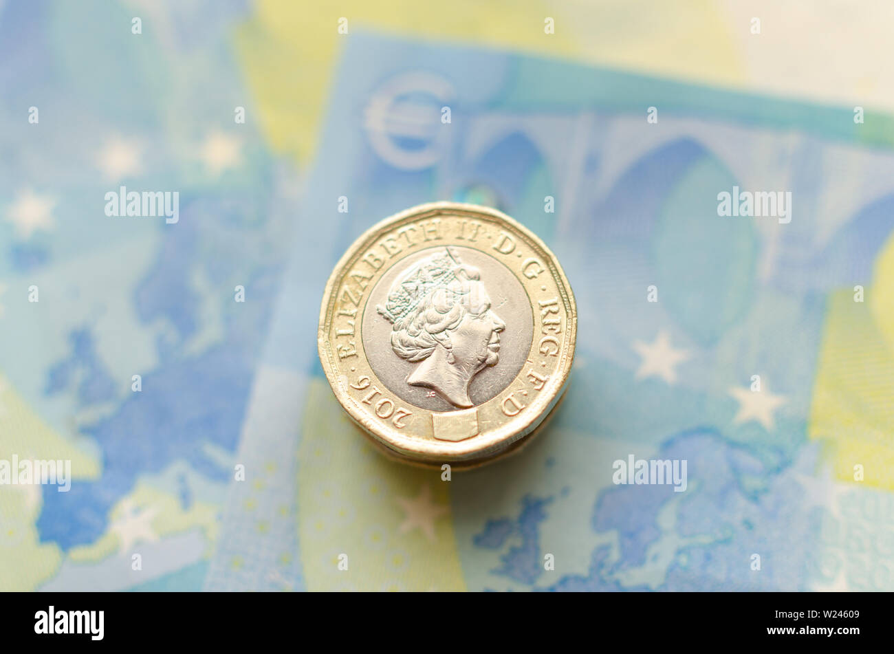 Close up photo of one Pound coins on top of 20 Euro banknotes. Stock Photo