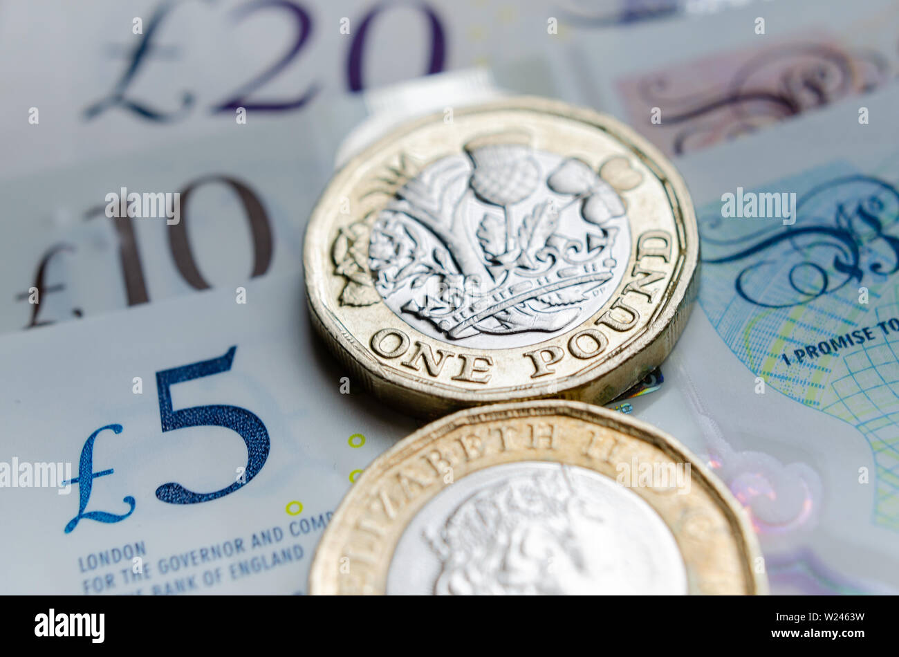 Macro photo of One Pound coins and the British pound banknotes of different denomination. Stock Photo