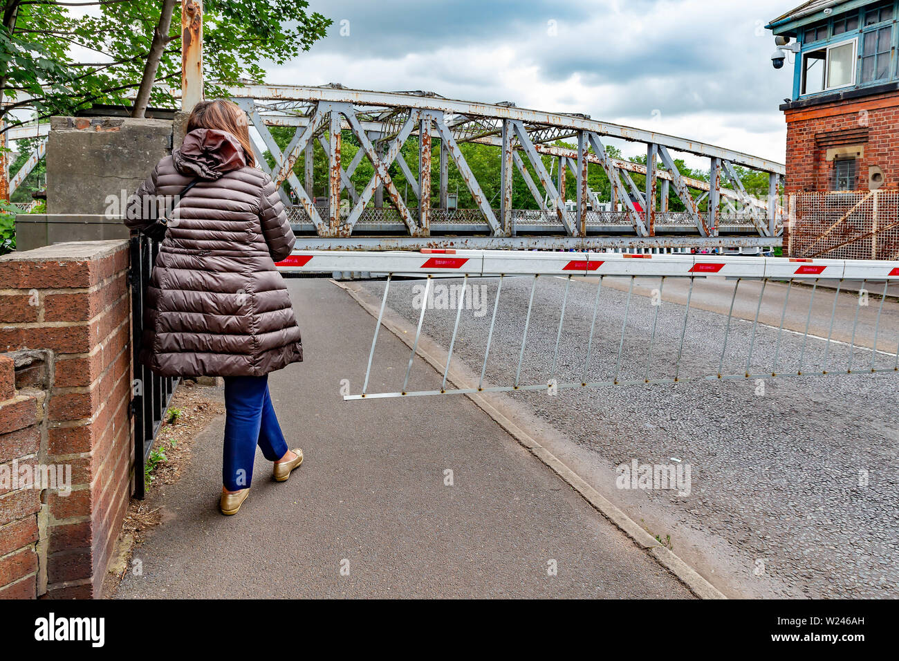 Woman waiting on the footpath at Stockton Heath swing bridge whilst a boat passes through Stock Photo