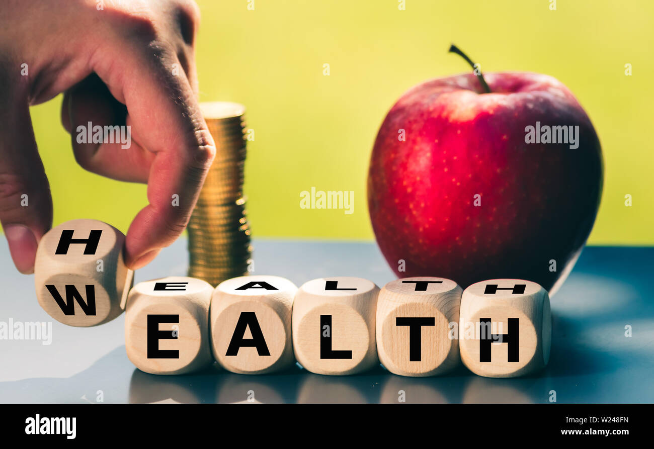 Hand is turning a dice and changes the word 'Health' to 'Wealth' Stock Photo