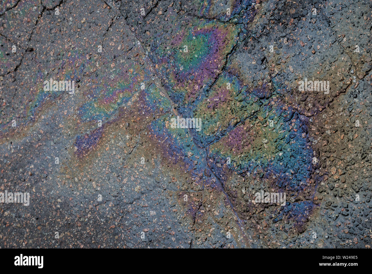 Close-up of an iridescent oil or gasoline spill on a wet asphalt, viewed from above. Top view. Stock Photo
