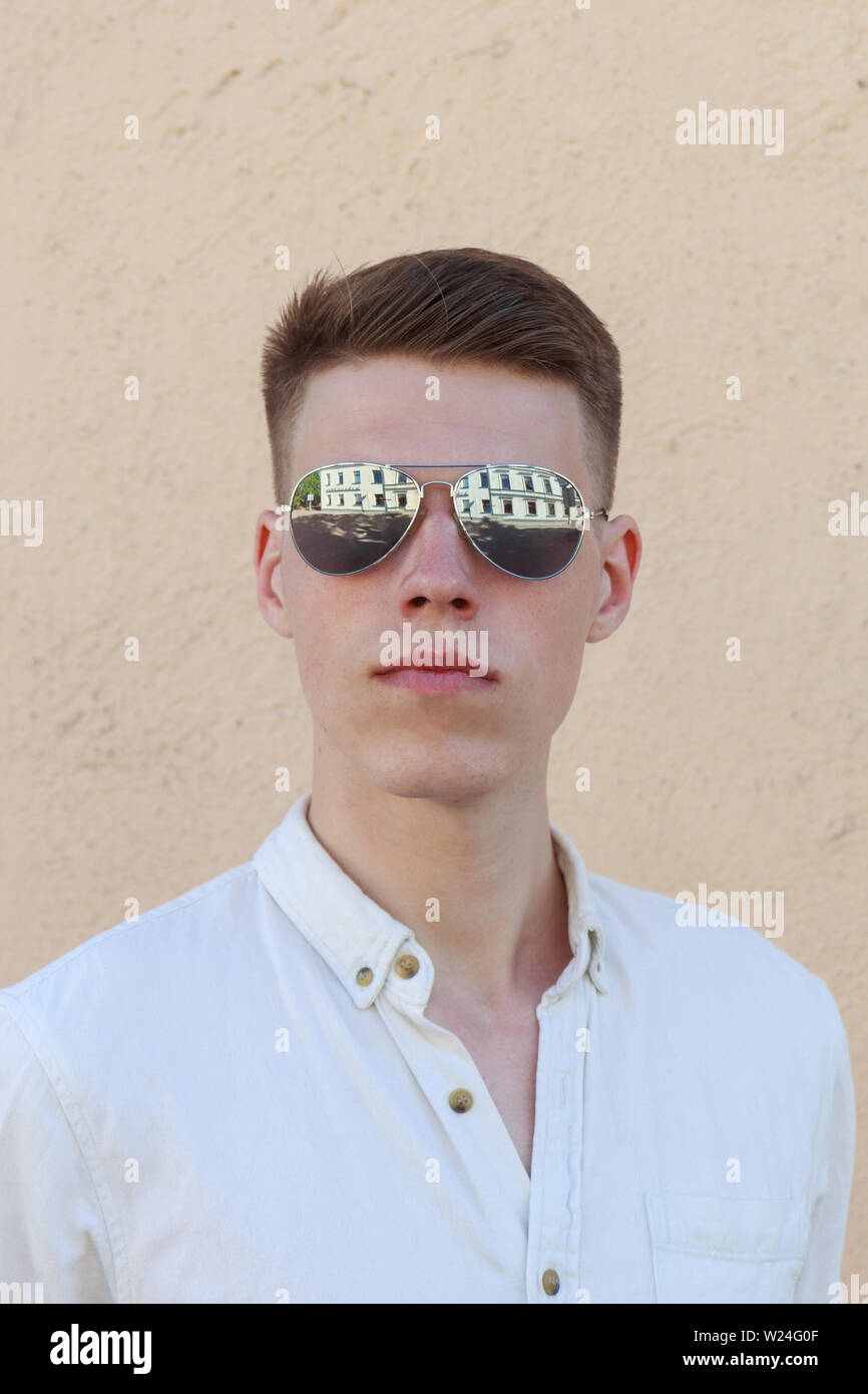 portrait of a handsome man dressed in white shirt against yellow wall ...
