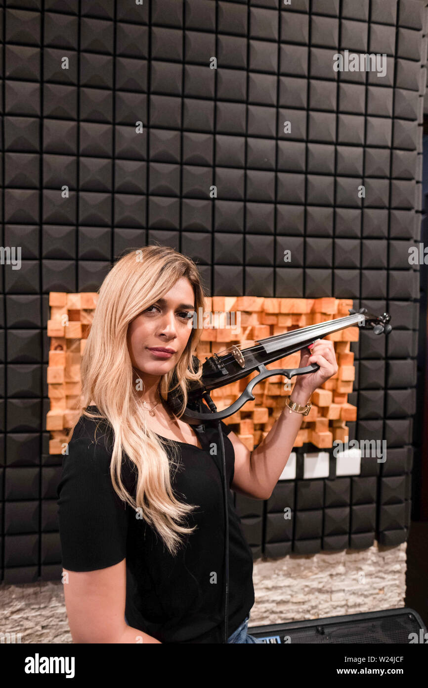 Portrait of a musician posing with electric violin in a music studdio